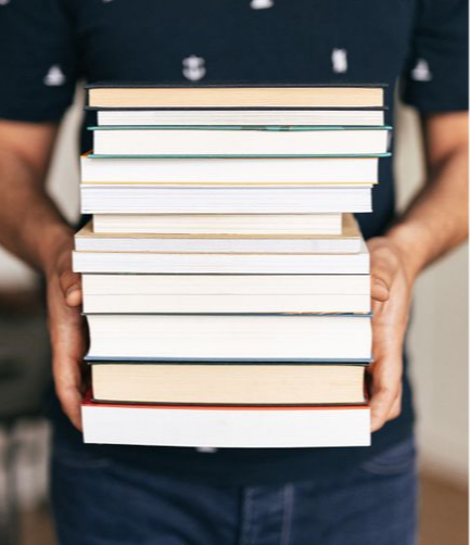 Teacher holding a tall stack of books
