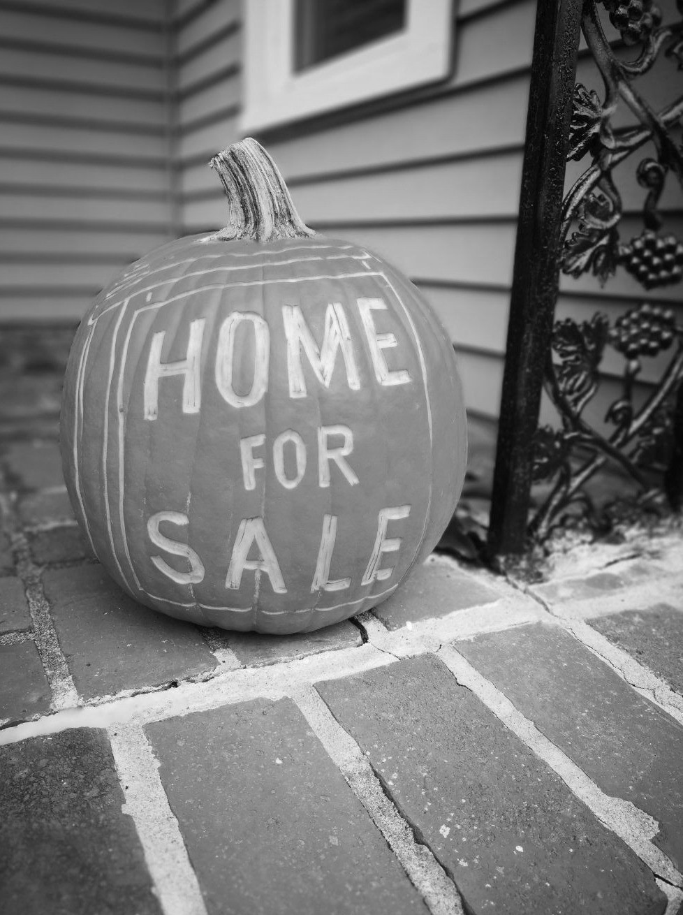 Pumpkin carved with Home for Sale on a front porch